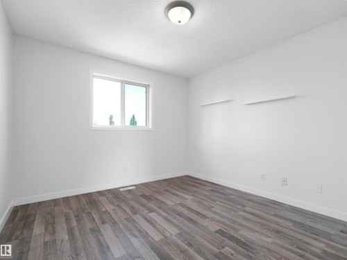 Wood-finish flooring, white walls, and a window with white trim, complemented by a ceiling-mounted light fixture - 2410 32B Street Nw, Edmonton, AB 