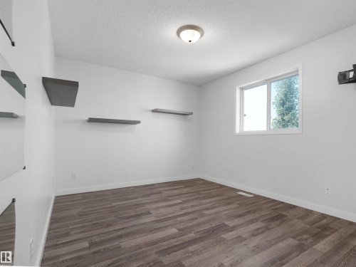 Wood-finish flooring, white walls, built-in shelving, and a prominent window - 2410 32B Street Nw, Edmonton, AB 