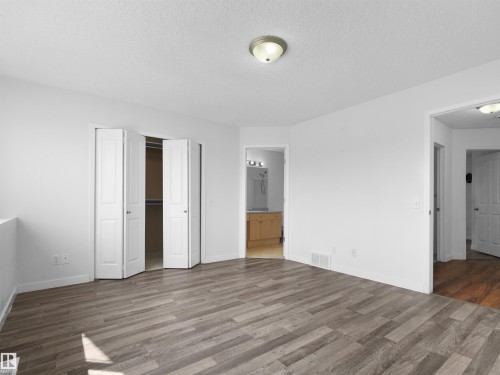 Wood-finish flooring, white bifold closet doors, and recessed lighting - 2410 32B Street Nw, Edmonton, AB 
