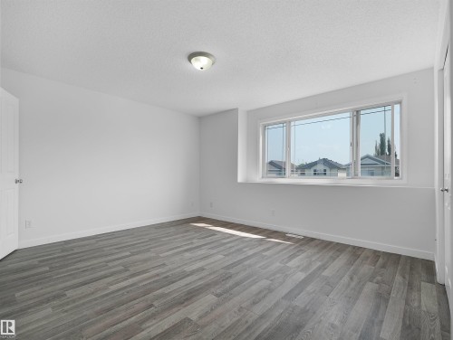 Grey wood-finish flooring, white walls, and a large window with white trim - 2410 32B Street Nw, Edmonton, AB 