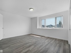 Grey wood-finish flooring, white walls, and a large window with white trim - 