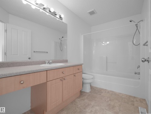 Wood-finish vanity with an integrated sink and light-toned countertop - 2410 32B Street Nw, Edmonton, AB 