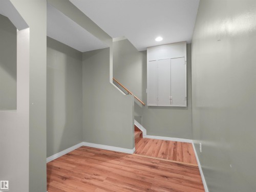 Wood-finish flooring, staircase with wood handrail, recessed lighting, and wall-mounted cabinetry - 2410 32B Street Nw, Edmonton, AB 
