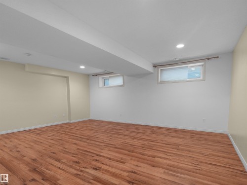 Spacious room featuring wood-finish flooring, recessed lighting, and two windows with blinds - 2410 32B Street Nw, Edmonton, AB 