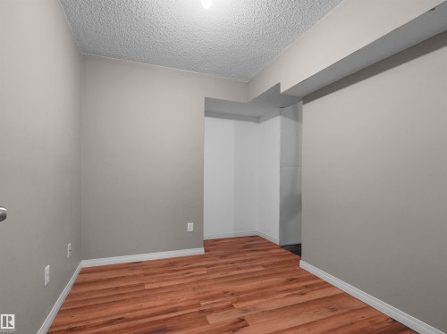 Wood-finish flooring with white trim, light gray painted walls, and textured ceiling finish - 2410 32B Street Nw, Edmonton, AB 