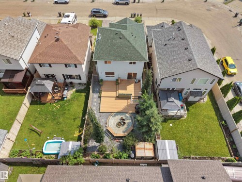 Lawned backyard featuring a wooden deck, built-in fire pit, and mature trees - 2410 32B Street Nw, Edmonton, AB 