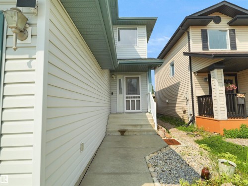 Fiber cement siding exterior with a concrete walkway, front entry door, and exterior lighting fixture - 2410 32B Street Nw, Edmonton, AB 
