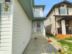 Fiber cement siding exterior with a concrete walkway, front entry door, and exterior lighting fixture - 