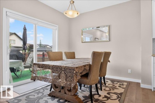 Dining area featuring wood-finish flooring, a contemporary overhead light fixture, and direct access to an outdoor space via a sliding glass door - 2709 Collins Crescent Sw Sw, Edmonton, AB - Indoor Photo Showing Dining Room