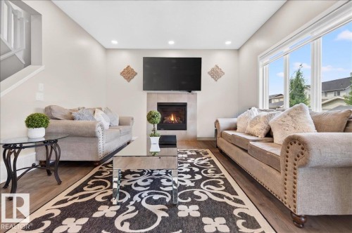 Bright living area with wood-finish flooring and a tiled fireplace - 2709 Collins Crescent Sw Sw, Edmonton, AB - Indoor Photo Showing Living Room With Fireplace