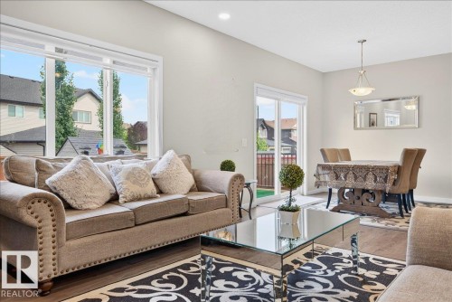 Open-concept living and dining area featuring wood-finish flooring, recessed lighting, and a sliding glass door to a private exterior space - 2709 Collins Crescent Sw Sw, Edmonton, AB - Indoor Photo Showing Living Room