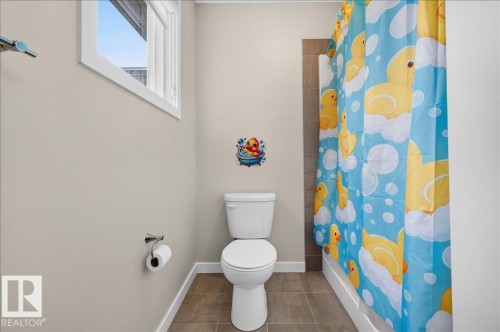 Bathroom featuring a white toilet, tile flooring, a window with white trim, and a shower with a tiled surround - 2709 Collins Crescent Sw Sw, Edmonton, AB - Indoor Photo Showing Bathroom