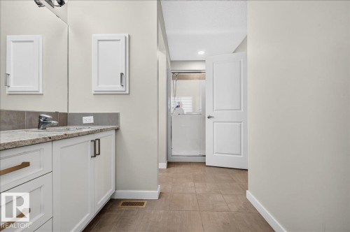 Bathroom featuring a dual-sink vanity with a light-toned countertop, white cabinetry with bronze hardware, and tile flooring - 2709 Collins Crescent Sw Sw, Edmonton, AB - Indoor Photo Showing Other Room