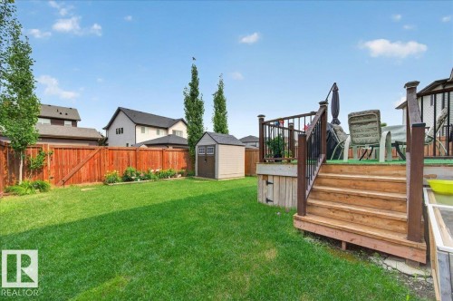 Expansive backyard featuring a lush lawn, privacy fencing, a wood deck with railings, and a storage shed - 2709 Collins Crescent Sw Sw, Edmonton, AB - Outdoor