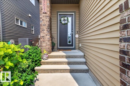 Inviting entry with concrete steps and dark-framed door featuring a decorative glass insert - 2709 Collins Crescent Sw Sw, Edmonton, AB - Outdoor