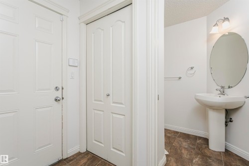 Pedestal sink with an oval mirror, wall-mounted vanity light, and a towel bar - 2407 Hagen Way Nw, Edmonton, AB 