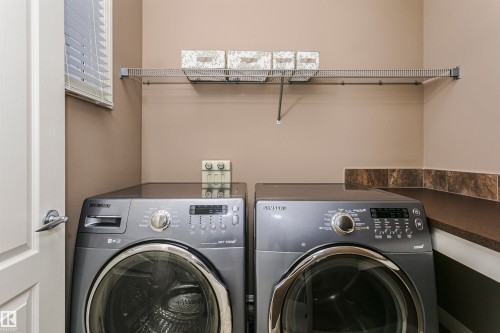 Dedicated laundry area featuring a wire storage shelf and a countertop with a tile backsplash - 2407 Hagen Way Nw, Edmonton, AB 