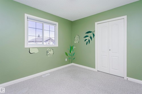 Light-colored carpeting, ample natural light, and a white bi-fold closet door - 2407 Hagen Way Nw, Edmonton, AB 