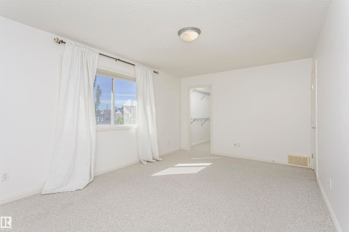 Expansive carpeted room featuring a single window and an open doorway leading to a closet with wire shelving - 2407 Hagen Way Nw, Edmonton, AB 