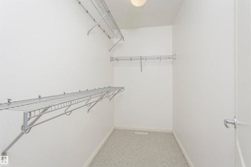 Recessed lighting illuminates the closet, featuring carpet flooring and multiple wire shelving units - 2407 Hagen Way Nw, Edmonton, AB 
