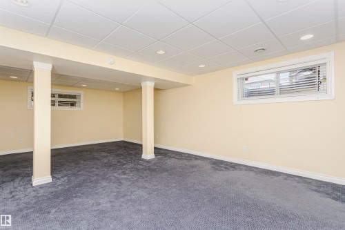 Recessed lighting illuminates this space featuring a drop ceiling, carpeted flooring, and two windows - 2407 Hagen Way Nw, Edmonton, AB 