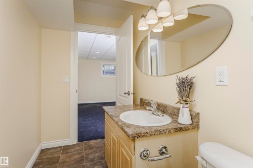 Vanity with an integrated sink and stone-look countertop, tile flooring, and overhead light fixture - 2407 Hagen Way Nw, Edmonton, AB 