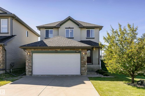 Two-story exterior featuring siding and stone accents, an attached garage, and a concrete driveway - 2407 Hagen Way Nw, Edmonton, AB 