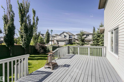 Spacious wooden deck with railing, siding exterior, and a manicured lawn - 2407 Hagen Way Nw, Edmonton, AB 