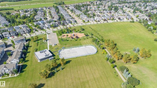 Expansive green space featuring a playground, paved walking paths, and a sports court - 2407 Hagen Way Nw, Edmonton, AB 