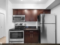 Full kitchen featuring stainless steel appliances, dark wood cabinetry, and stone countertops - 