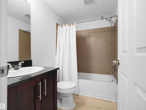 Dark wood-finish vanity with a dark countertop and integrated sink - #114 12035 22 Av Sw, Edmonton, AB 