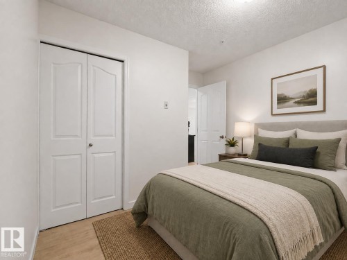 Wood-finish flooring, white paneled bifold closet doors, and white walls - #114 12035 22 Av Sw, Edmonton, AB 