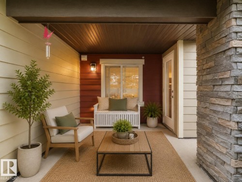 Covered outdoor porch featuring a stone accent wall, plank siding, and a paneled ceiling - #114 12035 22 Av Sw, Edmonton, AB 