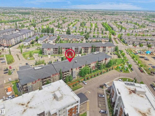 Multi-story building featuring balconies, surface parking, and surrounding green spaces - #114 12035 22 Av Sw, Edmonton, AB 