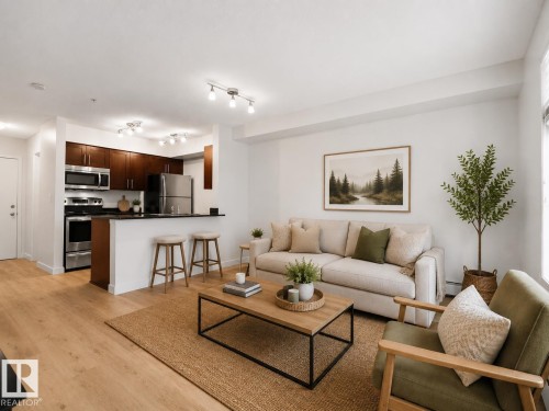 Open-concept layout featuring wood-finish flooring, dark wood cabinetry, stainless steel appliances, and track lighting - #114 12035 22 Av Sw, Edmonton, AB 