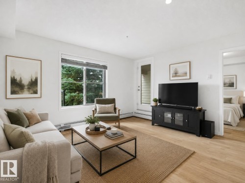 Hardwood-style flooring throughout, white walls, large window, and direct outdoor access - #114 12035 22 Av Sw, Edmonton, AB 