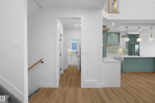 Open-concept living space featuring wood-finish flooring, recessed lighting, and a modern kitchen with a large island and pendant lighting - 142 Edgewater Circle, Leduc, AB 