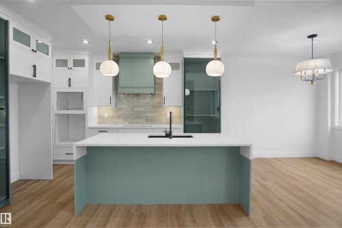 Modern kitchen featuring a spacious island with a white countertop and contrasting teal base - 142 Edgewater Circle, Leduc, AB 