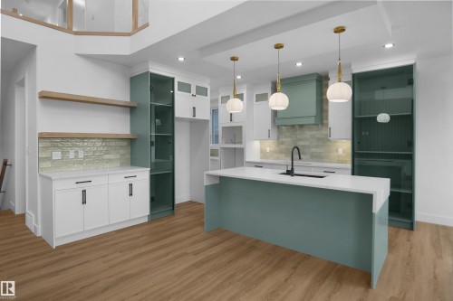 Open-concept kitchen featuring a large central island with a solid surface countertop, wood-finish flooring, and a glass-paneled built-in display cabinet - 142 Edgewater Circle, Leduc, AB 