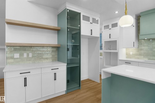 Modern kitchen featuring white cabinetry, a light blue-green island base, and a matching full-height glass-front pantry - 142 Edgewater Circle, Leduc, AB 