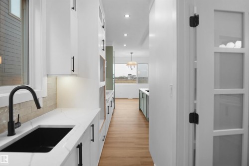Modern kitchen prep area featuring a black basin sink, matte black faucet, and white countertop - 142 Edgewater Circle, Leduc, AB 