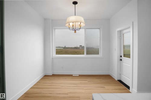 Room featuring wood-finish flooring, white baseboards, and a contemporary chandelier - 142 Edgewater Circle, Leduc, AB 
