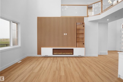 Spacious living area featuring a wood-slat accent wall, integrated media console with an electric fireplace, and wood-finish flooring - 142 Edgewater Circle, Leduc, AB 
