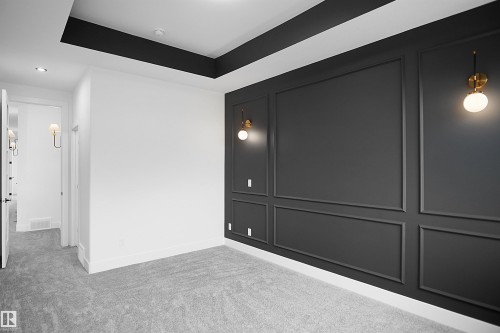 Interior room featuring a textured accent wall with applied molding, brass and frosted glass sconces, and recessed lighting - 142 Edgewater Circle, Leduc, AB 