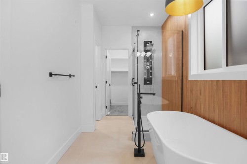 Contemporary bathroom featuring a freestanding tub with a floor-mounted faucet, a glass-enclosed shower with a multi-function panel, and a wood-slat accent wall - 142 Edgewater Circle, Leduc, AB 