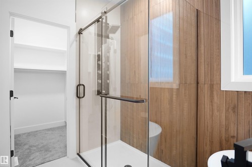 Glass-enclosed shower featuring a multi-jet panel and dark-framed sliding door - 142 Edgewater Circle, Leduc, AB 
