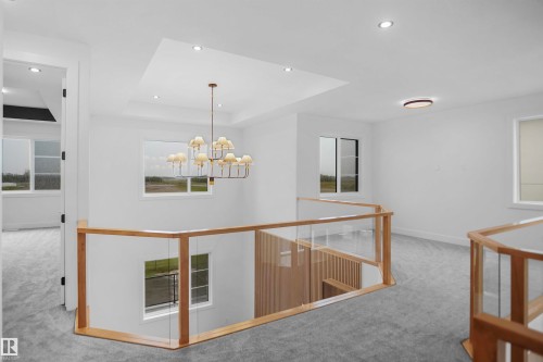Open landing area featuring a contemporary chandelier, recessed lighting, and a glass-paneled railing with wood-finish trim - 142 Edgewater Circle, Leduc, AB 