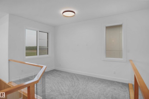 Carpeted room featuring a modern ceiling light fixture, white trim, and two windows - 142 Edgewater Circle, Leduc, AB 