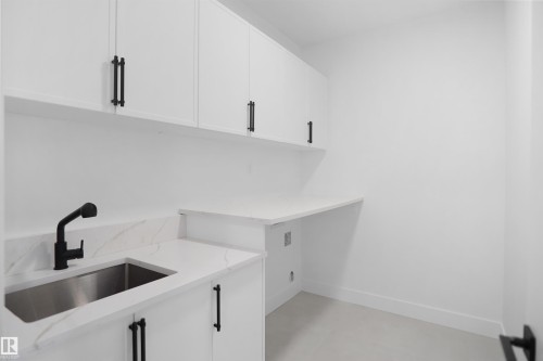 Modern utility room featuring white cabinetry with matte black hardware, white countertops, stainless steel sink, and a matte black faucet - 142 Edgewater Circle, Leduc, AB 