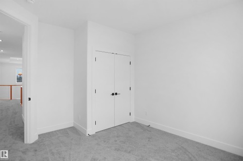 Interior room featuring light gray carpet, white walls, and a double-door closet with black hardware - 142 Edgewater Circle, Leduc, AB 